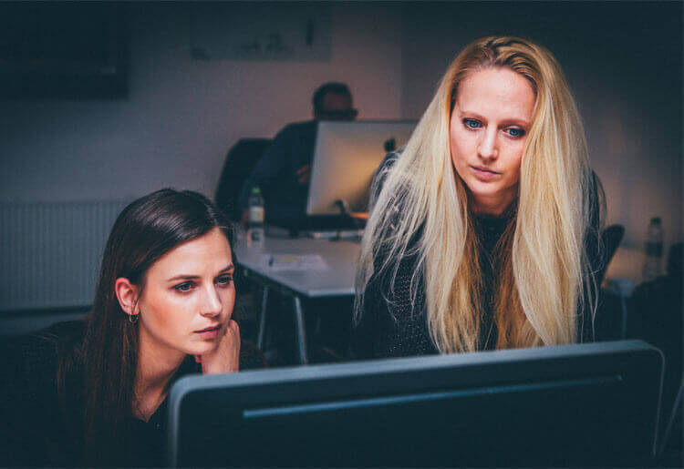 two girls looking over computer 